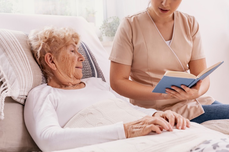 Woman reading to elderly woman